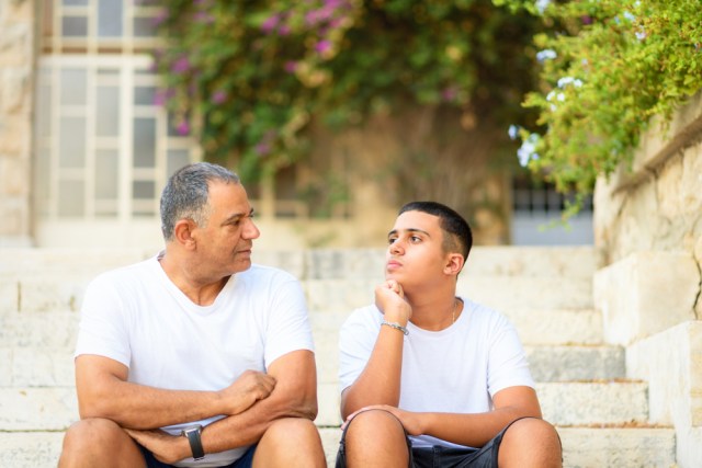 Father and son sitting on steps looking thoughtful.  